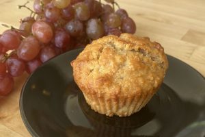 banana muffin on black saucer with grapes beside it