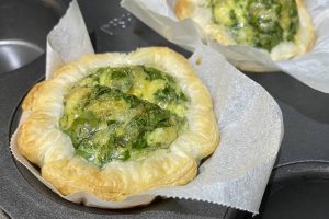 two cheese and spinach mini quiches in a cupcake tray lined with baking paper